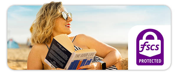 Image of a woman lying on the beach reading a book called The Good Life